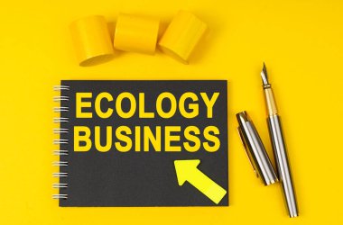 İş ve finans kavramı. Sarı bir arka planda bir kalem, siyah bir defter bulunur - ECOLOGY İŞ