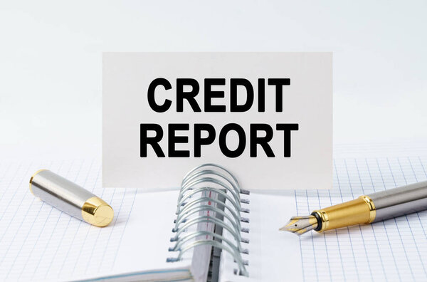 Финансы и бизнес-концепция. На столе ноутбук, ручка и визитная карточка с надписью - КРЕДИТ ДОКЛАД