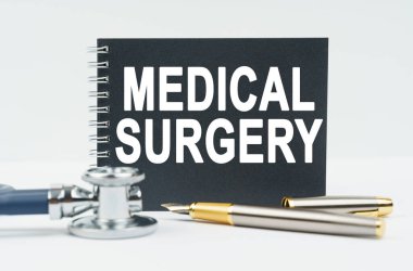 Tıp ve sağlık konsepti. Beyaz arkaplanda bir steteskop, bir kalem ve siyah bir defter bulunur.