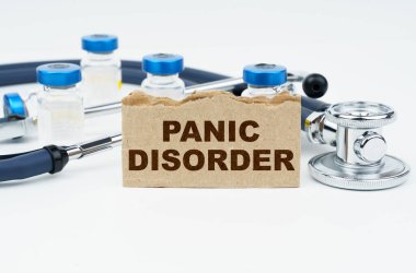 Tıp ve sağlık konsepti. Beyaz bir masada ampuller, bir steteskop ve üzerinde PANIC DISORDER yazan bir karton bulunur.