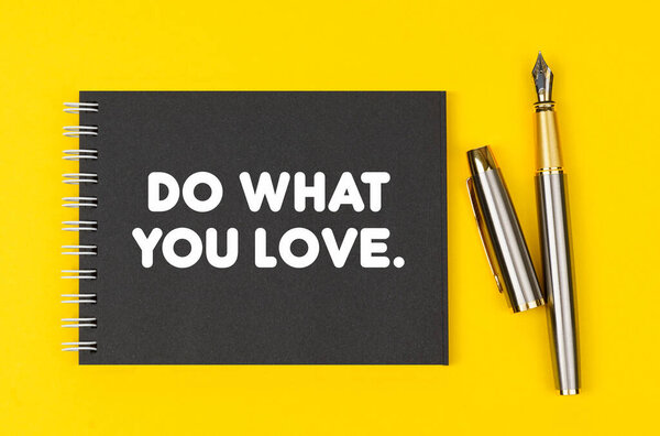 Business and finance concept. On a yellow background lies a pen and a black notebook with the inscription - Do What You Love