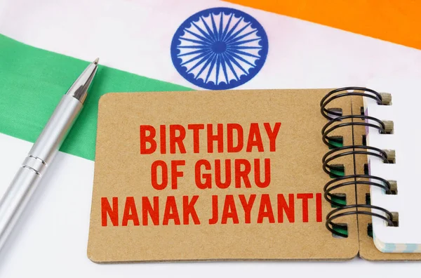 Holidays in India. Against the background of the flag of India lies cardboard with the inscription - Birthday of Guru Nanak Jayanti