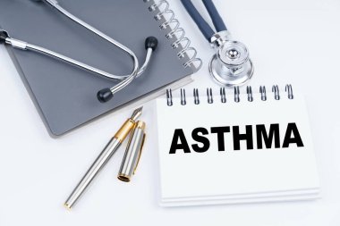 Tıp ve sağlık konsepti. Masanın üzerinde steteskop, kalem ve üzerinde ASTHMA yazan bir defter var.