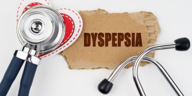 Tıp ve sağlık konsepti. Beyaz bir masada bir kalp, bir steteskop ve üzerinde yazı olan bir karton bulunur.