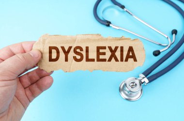Tıp ve sağlık konsepti. Mavi arka planda, bir adam üzerinde DYSLEXIA yazan bir karton kutu tutuyor.