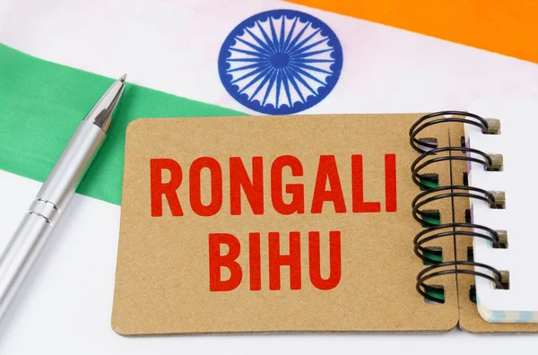 Holidays in India. Against the background of the flag of India lies cardboard with the inscription - Rongali Bihu