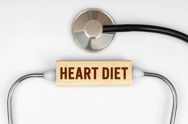Health and medicine concept. On the table is a stethoscope and a wooden plate with the inscription - HEART DIET