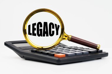 Finans ve iş konsepti. Beyaz arkaplanda bir hesap makinesi ve üzerinde LEGACY yazan bir büyüteç bulunur.