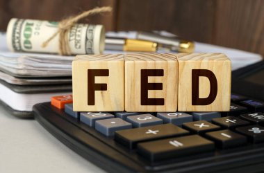 Finans ve ekonomi kavramı. Masanın üzerinde para, hesap makinesi, bir defter ve üzerinde FED yazan küpler var.