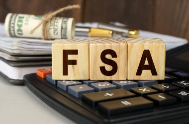 Finans ve ekonomi kavramı. Masanın üzerinde para, hesap makinesi, bir defter ve üzerinde FSA yazan küpler var.