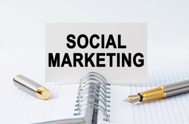 Finans ve iş konsepti. Masanın üzerinde bir defter, bir kalem ve üzerinde SOSYAL MARKETING yazan bir kartvizit var.