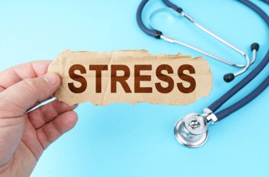 Tıp ve sağlık konsepti. Mavi arka planda, bir adam üzerinde STRESS yazan bir karton kutu tutuyor.