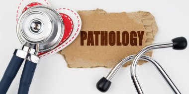 Tıp ve sağlık konsepti. Beyaz bir masada bir kalp, bir steteskop ve üzerinde patoloji yazılı bir karton bulunur.