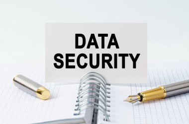 Finans ve iş konsepti. Masanın üzerinde bir defter, bir kalem ve üzerinde DATA Güvenlik yazan bir kartvizit var.