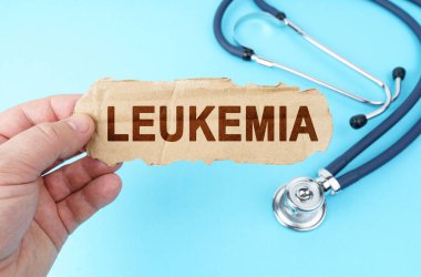 Medicine and health concept. On a blue background, a man holds a cardboard box with the inscription - LEUKEMIA