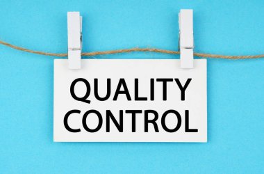 Medicine and health concept. On a blue background, a white plaque hangs on a rope with the inscription - QUALITY CONTROL