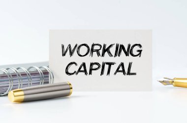 Business and finance concept. On the table is a notebook, a pen and a business card with the inscription - WORKING CAPITAL