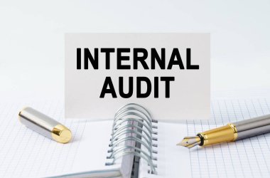 Finance and business concept. On the table is a notebook, a pen and a business card with the inscription - INTERNAL AUDIT