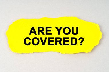 Business and finance concept. On a white background lies yellow paper with the inscription - ARE YOU COVERED