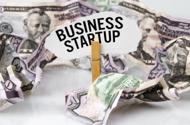 İş ve finans kavramı. Masada dolarlar var ve üzerinde kağıt olan bir mandal var - İŞ STARTUP