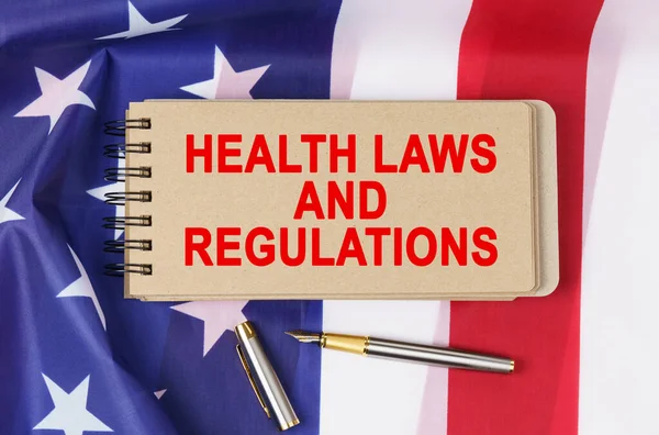 Law and order concept. Against the background of the flag of the United States of America lies a notebook with the inscription - HEALTH LAWS AND REGULATIONS