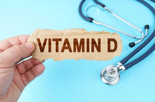 Tıp ve sağlık konsepti. Mavi arka planda, bir adam üzerinde VITAMIN D yazan bir karton kutu tutuyor.