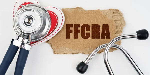 医学和健康概念 白桌子上躺着一颗心 一个听诊器和一块写着 Ffcra 字样的纸板 — 图库照片