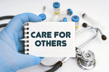 Tıp konsepti. Masanın üzerinde steteskop var, doktor elinde bir defter tutuyor - diğerleri için bakım