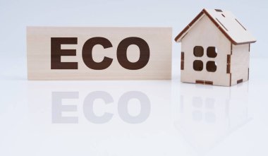 ECO ve iş konsepti. Masada ahşap bir ev ve ECO tabelası var.