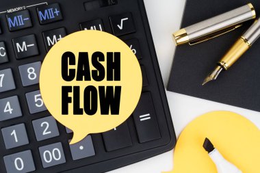 İş ve ekonomi kavramı. Hesap makinesi, kalem, keçeli kalem ve üzerinde para akışı yazan bir çıkartma var.