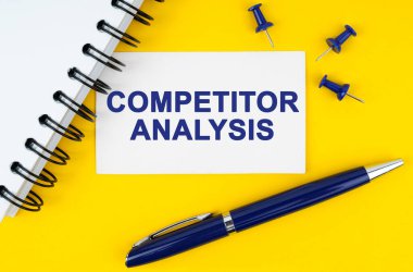 İş ve finans kavramı. Sarı arka planda bir defter, bir kalem ve üzerinde COMPETITOR ANALYSIS yazan bir kartvizit bulunur.