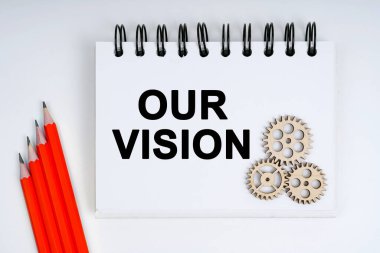 İş ve finans kavramı. Beyaz arka planda kırmızı kalemler, dişliler ve üzerinde bizim vizyonumuz yazan bir defter var.