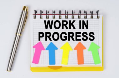 İş ve finans kavramı. Beyaz bir arkaplanda bir kalem ve bir defter yatar - ProgRESS İÇİN İÇİN