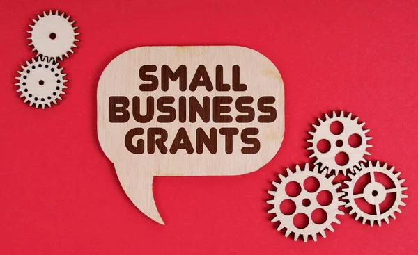 Business and finance concept. On a red background, gears and a thought plate with the inscription - Small Business Grants