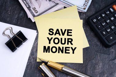 Finans ve iş konsepti. Masanın üzerinde bir hesap makinesi, bir kalem, para ve üzerinde yazı olan çıkartmalar var.