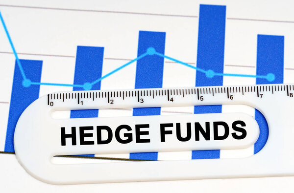 Концепция экономики. на листе с графиками стоит белая линейка с надписью - хеджевые фонды