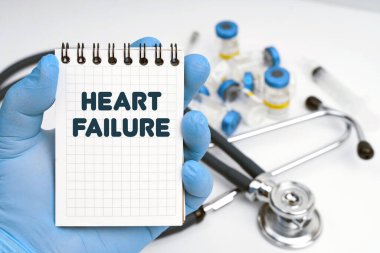 Tıp konsepti. Masanın üzerinde steteskop var, doktor elinde bir defter tutuyor - kalp yetmezliği