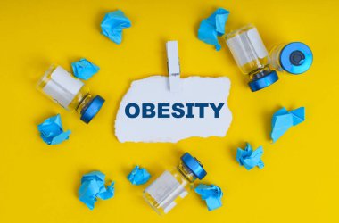 Tıp ve sağlık konsepti. Sarı arka planda ampuller, mavi buruşuk kağıt ve yazılı kağıt - OBESİT
