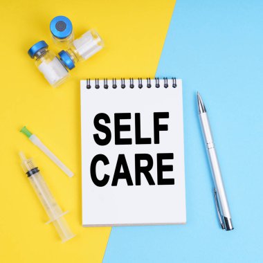 Tıp ve sağlık konsepti. Bir şırınga, ampuller ve yazıtlı bir defter - SELF CARE