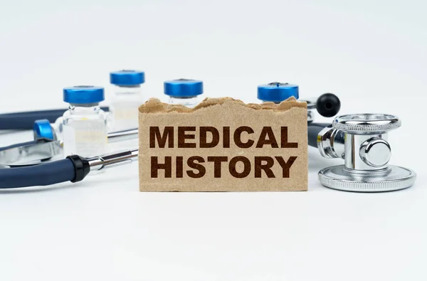 医学和健康概念 在一张白色的桌子上躺着安培 一个听诊器和一个印有题词的硬纸板 医学上的门 — 图库照片