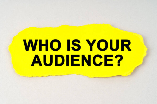 Business and finance concept. On a white background lies yellow paper with the inscription - WHO IS YOUR AUDIENCE