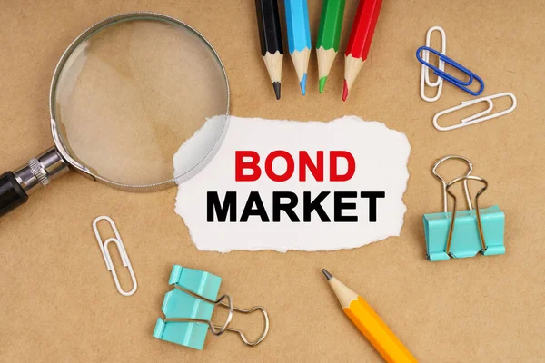 Business concept. On the table are pencils, paper clips, a magnifying glass and paper with the inscription - BOND MARKET