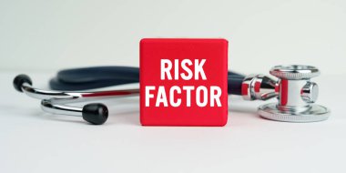 Tıp ve sağlık konsepti. Masanın üzerinde bir steteskop ve üzerinde RISK FACTOR yazan kırmızı bir küp var.