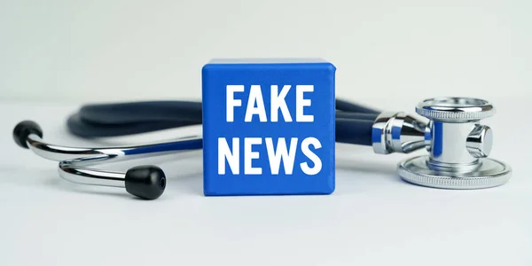 医学と健康の概念 テーブルの上には 碑文付きの聴診器と青い立方体があります Fake News — ストック写真