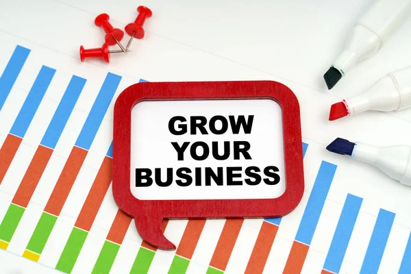 Business and economy concept. There are markers, charts and a sign on the table - GROW YOUR BUSINESS