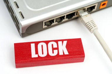 İnternet ve güvenlik kavramı. Masanın üzerindeki ağa bağlı bir yönlendirici var, üzerinde yazı olan bir plaketin yanında - Kilitle