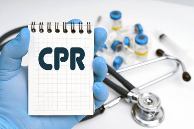 Tıp konsepti. Masanın üzerinde steteskop var, doktor elinde bir defter tutuyor - kalp masajı