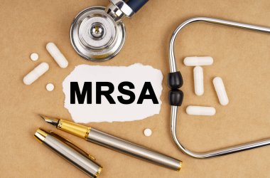 Tıp ve sağlık konsepti. Masanın üzerinde steteskop, haplar, üzerinde MRSA yazan bir kalem ve kağıt var.