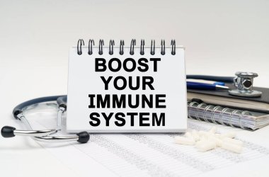 Tıp ve sağlık konsepti. Masanın üzerinde steteskop, günlük ve üzerinde yazılar olan bir defter var. Bağışıklık sisteminizi destekleyin.