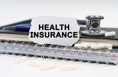 Tıp ve sağlık konsepti. Masanın üzerinde bir stetoskop, bir günlük ve yazılı bir kağıt parçası var.